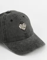 Gorra de denim color gris oscuro con visera curva y ajuste trasero. Presenta un parche en forma de corazón con estampado animal print en el frente.