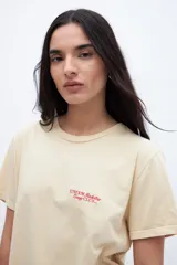 Remera color crema con estampado pequeño en el pecho con la leyenda "UNFRM. Redefining Energy Club".