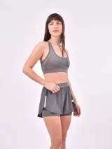 Short deportivo negro de doble capa, con una capa exterior suelta y una capa interior ajustada tipo calza. Presenta un detalle vertical blanco en el lateral derecho.