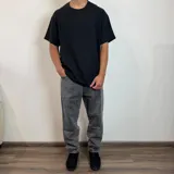 Jean de hombre color negro con efecto lavado, de corte mom fit, con cintura elástica y puños ajustados en los tobillos.