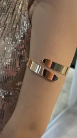 Brazalete dorado rígido, abierto, para usar en el brazo.