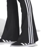 Calza Adidas negra con corte ajustado, cintura elástica, perneras acampanadas y tres rayas blancas en los laterales.