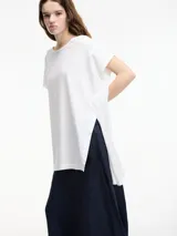 Remera blanca de algodón, corte amplio y largo irregular con tajos laterales.