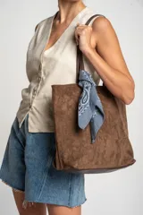 Bolso tipo tote de gamuza vegana color camel, con asas de mano y logo grabado en el frente.