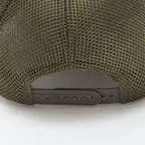 Gorra de gabardina color gris con paneles de malla verde en la parte trasera. Tiene bordado frontal con la palabra 'Houston' en azul y naranja sobre un óvalo blanco con borde marrón.