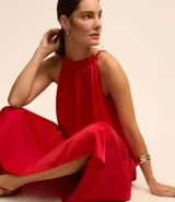 Vestido midi satinado color rojo, sin mangas, con cuello fruncido y cierre por lazo trasero.