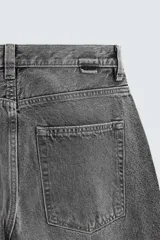 Pantalón de jean gris oscuro, corte amplio, con cinco bolsillos, efecto lavado y cierre frontal con cremallera y botón.