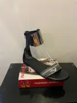 Sandalias gladiadoras negras con tira delantera con estampado de piel de serpiente, cierre trasero con cremallera y pulsera metálica dorada en el tobillo.