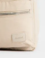 Mochila negra de tela deportiva con bolsillo frontal con cierre y tirador de cordón y goma. Tiene correas regulables, manija superior, doble cierre superior y etiqueta de goma.