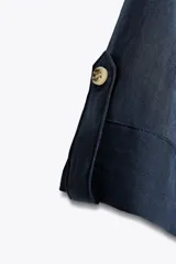 Camisa azul marino de cuello solapa con escote pico y manga ancha por debajo del codo con trabilla y botón. Cierre frontal con botones.