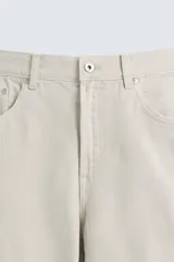 Pantalón de jean color beige, corte recto y relajado, con cintura ajustable con cordón interior, cinco bolsillos, efecto lavado y cierre frontal con cremallera y botón.