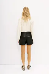 Short cargo negro de cuero vacuno, con múltiples bolsillos frontales con cierres y solapas. Corte por encima de la rodilla.