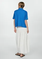 Camisa blanca de lino con cuello clásico, manga corta y cierre frontal con botones.