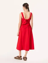 Vestido midi rojo de poplin con lycra, corte evasé, breteles anchos, bolsillos laterales y tajo frontal. Se ajusta en la espalda con un lazo.