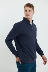 Remera verde de manga larga con cuello alto y cierre de cremallera.