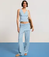 Pantalón celeste de corte recto, cintura alta, con canesú sobrepuesto y lazo lateral.