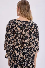 Kimono corto negro con estampado floral en tonos beige, con mangas 3/4 y lazo de ajuste en la cintura.