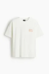 Remera blanca de algodón de corte holgado con estampado del artista Keith Haring en el pecho. Modelo de H&M con cuello redondo y mangas cortas.