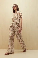 Pantalón ancho de tela liviana con estampado de hojas color crema sobre fondo azul. Tiene cintura elastizada con lazo ajustable.