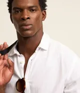 Camisa celeste de lino con cuello camisero, abotonadura frontal y mangas largas.