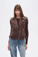 Chaleco estilo biker de eco-cuero color marrón oscuro, con solapas anchas, cierre frontal asimétrico y detalles de tachas plateadas. Presenta cinturón ajustable con hebilla en el ruedo.