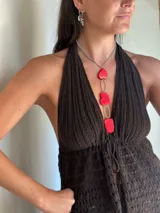 Collar con cadena de eslabones plateados y dije colgante compuesto por tres piezas de piedra roja teñida (dos de forma irregular y una ovalada) separadas por eslabones metálicos plateados.