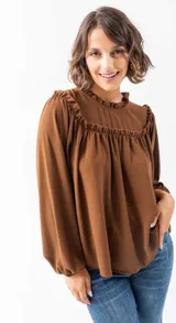 Camisa marrón de poliéster con cuello redondo con volados y mangas largas abullonadas.