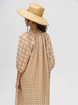 Vestido midi color beige con estampado de círculos y cuello mao, con mangas 3/4 abullonadas y cierre frontal con botones. Incluye cinturón de cuero marrón.