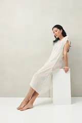 Top largo color blanco, confeccionado en tejido liviano con transparencia y caída fluida.