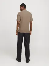 Polo de punto color beige, con cuello clásico, mangas cortas y cierre con botones.