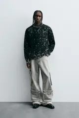 Pantalón relaxed fit de denim negro con efecto lavado, bolsillos frontales, traseros de plastrón y multifunción en perneras. Bajo ajustable con trabilla y cierre frontal con cremallera y botón.