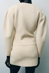 Minifalda color crema de punto liso, tiro alto, cintura elástica y corte evasé.
