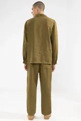 Chaqueta color verde oliva confeccionada en lino, con cuello camisero, cierre frontal con botones, manga larga con puños abotonados, un bolsillo de parche en el pecho y dos bolsillos de parche en la parte inferior.