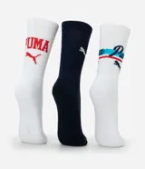 Kit de tres pares de medias Puma de caña alta, confeccionadas en algodón más sostenible. Incluye un par blanco con logo rojo, un par azul marino con logo blanco y texto, y un par blanco con logo y diseño deportivo en azul y rojo.