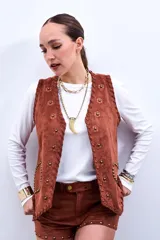 Chaleco marrón de gamuza sintética con apliques de flores y tachas doradas.