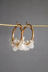 Aros dorados tipo argolla con colgantes de piedras blancas y transparentes.