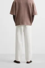 Pantalón color arena de corte recto, confeccionado en tejido de algodón y lino. Cuenta con cintura elástica ajustable con cordón, bolsillos delanteros y traseros de parche.