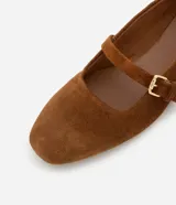 Zapatilla chatita femenina en gamuza color marrón, con punta redonda y tira con hebilla lateral.