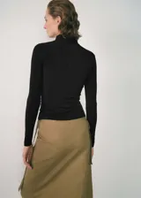 Camiseta negra de cuello alto con diseño cruzado y mangas largas.