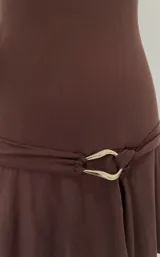 Vestido corto marrón con escote off-shoulder, mangas cortas y falda corta acampanada con detalle de cinturón con hebilla dorada.
