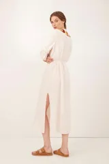 Saco color crudo con bordado de flechas en tonos ocre, rojo y marrón. Tiene mangas largas con detalle de puntilla y lazo en la cintura.