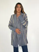 Saco largo de punto con diseño a rayas horizontales en tonos celeste y beige, con cuello esmoquin y mangas largas.