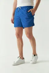 Short de baño liso color celeste, con cintura elástica ajustable con cordón, dos bolsillos laterales y uno trasero.