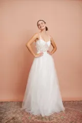 Vestido largo de fiesta color blanco, con breteles finos, corpiño con ballenas y apliques de flores bordadas. Falda de microtul con brillo.