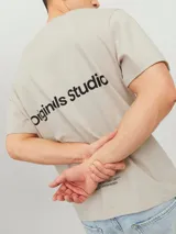 Camiseta color crema de manga corta y cuello redondo con estampado en la espalda que dice 'Originals Studio' y 'Brought to you by Org Dept. Designed in Copenhagen'.