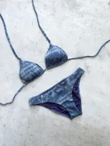 Conjunto de bikini negro con textura, compuesto por un corpiño de triángulos movibles con tirantes finos y una bombacha vedetina ancha con laterales fijos.