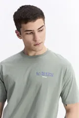 Remera de manga corta color verde menta, con escote redondo y fit regular. Presenta un estampado en la espalda con la frase "NO RULES! BREAK THE RULES" y un diseño abstracto en tonos azules y blancos.