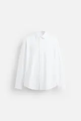 Camisa blanca de corte regular fit, con cuello italiano, manga larga con puños abotonados y cierre frontal con botones.