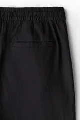 Pantalón negro de corte recto, confeccionado en mezcla de lino y algodón. Presenta cintura elástica con cordón ajustable, bolsillos laterales y bolsillo trasero insertado.