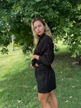 Conjunto negro de camisa de manga larga con botones y shorts.